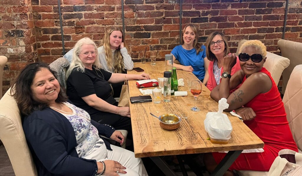 Six smiling people from CMT Engineering sitting around a wooden table at the Cherrywood Smokehouse Bar & Grill