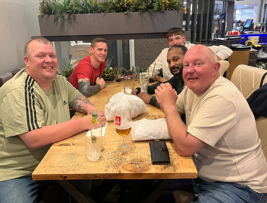 Five people from CMT Engineering sitting around a wooden table Six smiling people from CMT Engineering sitting around a wooden table at the Cherrywood Smokehouse Bar & Grill